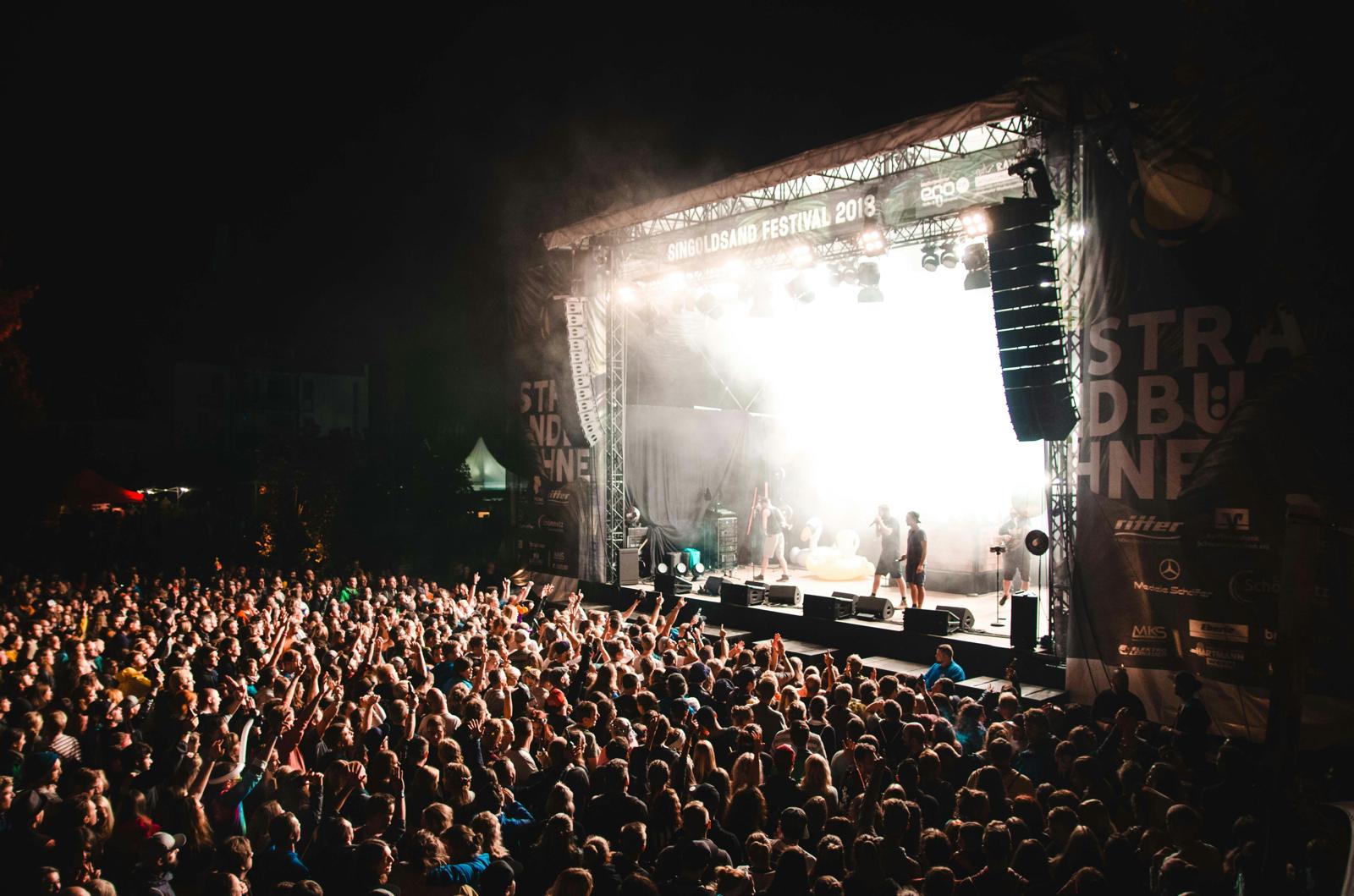 Openluchtpodium met publiek tijdens een avondconcert